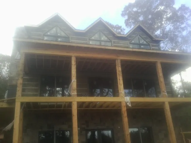 Dormers and porch framing on a large log home under construction — Roof Coating work by our crew in Ovid